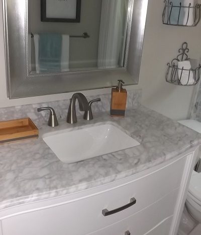 Custom granite tiled vanity with stainless steel mirror.