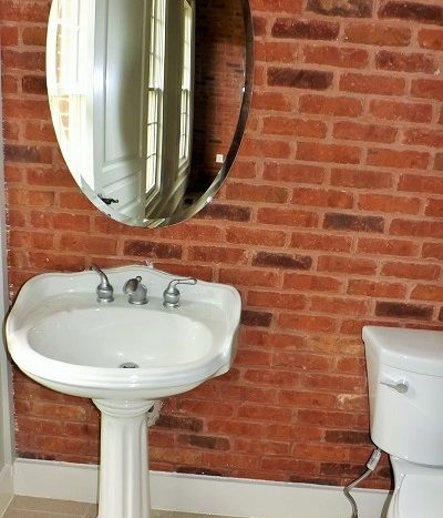 powder room with pedestal sink, tile and brick exposed walls