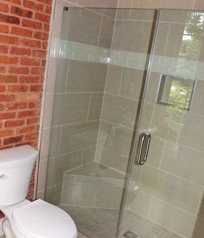 bath with glass shower, tiled walls, tiled shower and floors